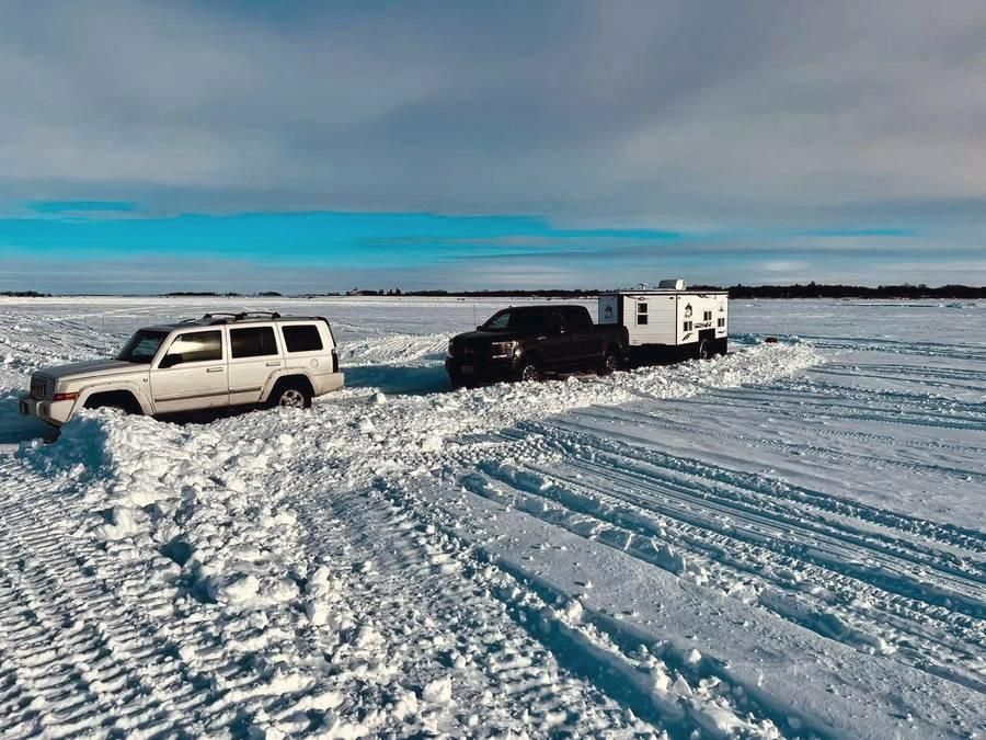 Trucks pulling wheelhouses onto the ice road on Devils Lake