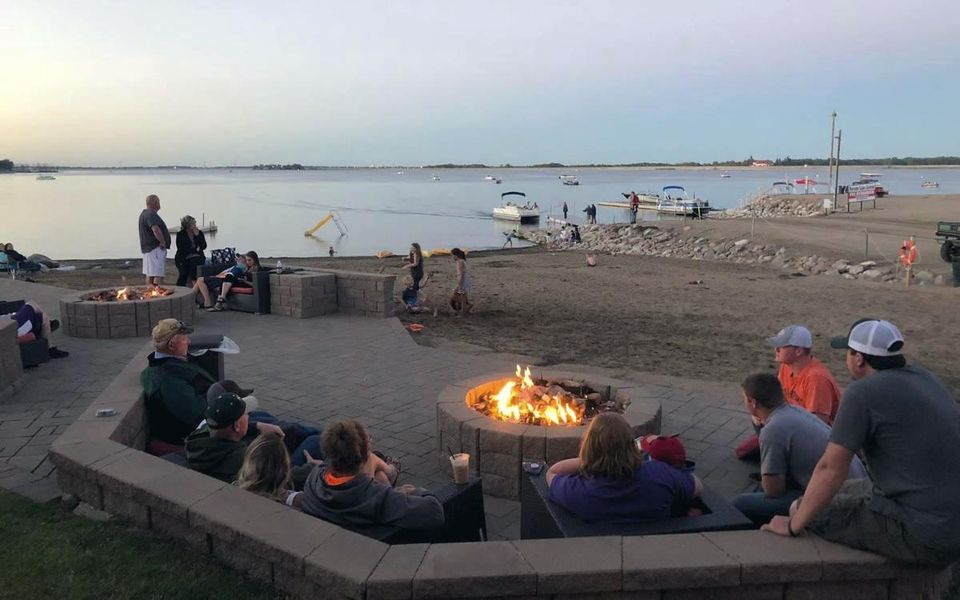 Guests around the lakeside fire pit at dusk